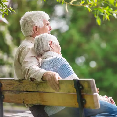 Older couple sitting together outdoors while discussing retirement and Medicare planning